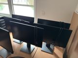 three computer monitors sitting on top of a wooden desk