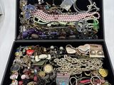 une boîte noire remplie de nombreux bijoux, posée sur une table