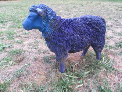 une statue bleue représentant un mouton debout dans l'herbe