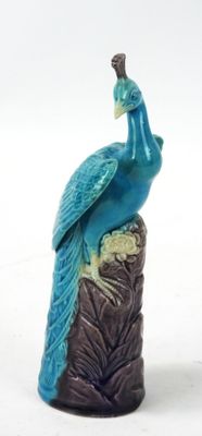 figurine de paon perchée sur une souche d'arbre, sur fond blanc