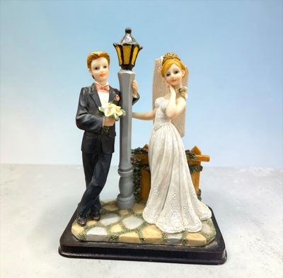 figurines of a bride and groom standing next to a street light