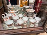 many cups and saucers on display in a glass case