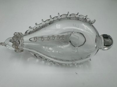 une bouteille en verre transparent avec une poignée argentée posée sur un fond blanc