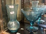 two blue glass vases on display in a glass case
