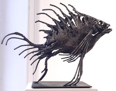 une sculpture métallique représentant un poisson sur un socle