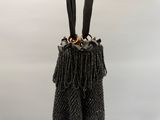 le sac orné de perles noires est accroché à la poignée du sac à main