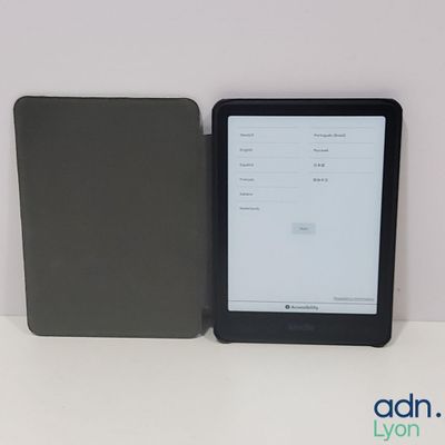 une tablette posée sur une table, à côté d'un livre