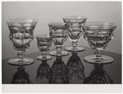 photographie en noir et blanc représentant plusieurs verres à vin posés sur une table