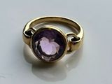 an image of a gold ring with a purple stone in the center