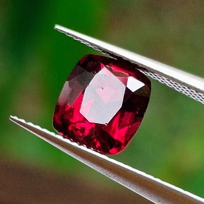 a close up view of a red diamond being held by a pair of pliers