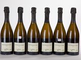 six bouteilles de vin sont alignées sur une surface blanche