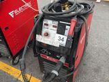 an electric welding machine sitting in a parking lot next to other equipment