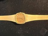 yellow leather watch band with a gold face on a black surface