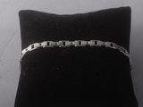 silver bracelet on a black cushion on a white surface
