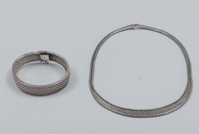 two pieces of silver jewelry on a white surface