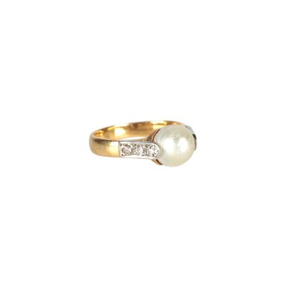 un gros plan d'une bague en or sertie d'une perle blanche et de diamants