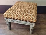 a small stool with a patterned seat on the floor