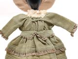 une poupée d'antan vêtue d'une robe verte et d'un chapeau