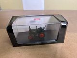 un tracteur miniature dans une boîte transparente posée sur une table