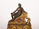 une statue d'un homme assis au sommet d'une horloge