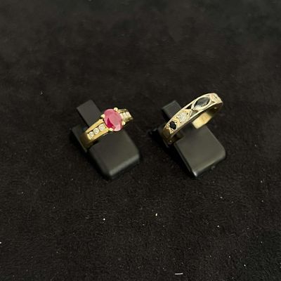 pair of gold rings with a pink stone on a black surface