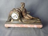 une statue en bronze représentant une femme assise sur une horloge