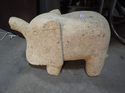 une statue d'éléphant en pierre posée par terre dans un garage