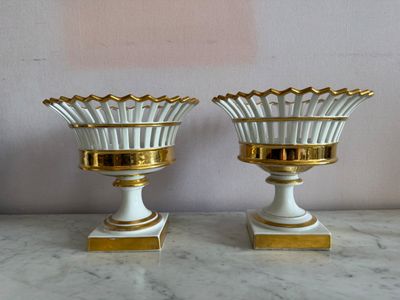 deux vases blancs et dorés posés sur une table en marbre