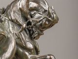 bronze statue of a man riding a horse on a wooden table
