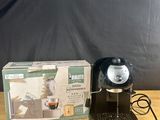 the coffee maker is sitting on the table next to the box