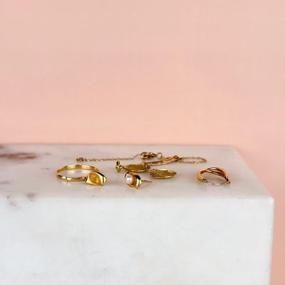 gold rings on a white marble block against a pink background