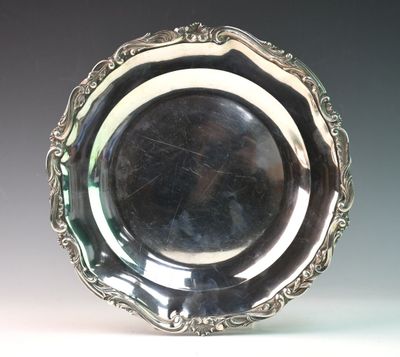 an antique silver plate with a decorative design on the rim