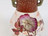a small vase with a flower on it on a white surface