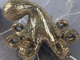 brass octopus figurine on a marble surface next to a vase