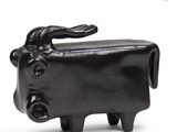 a small black cow figurine sitting on a white surface