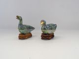 pair of ceramic ducks on wooden stands on a white surface
