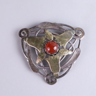 a silver brooch with a red stone in it