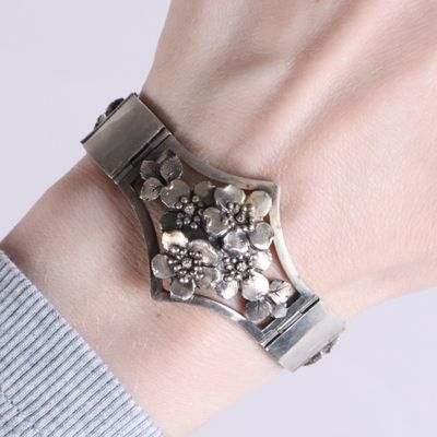 a woman wearing a silver bracelet with flowers on it