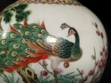 a vase with a peacock painted on it on a table