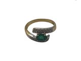 gros plan d'une bague en or avec une pierre verte