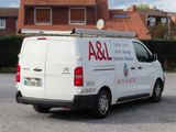 a white van parked in a parking lot with a house in the background