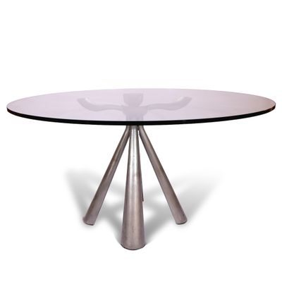 une table ronde en verre avec trois pieds en métal et un plateau en verre