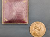 une image représentant une petite médaille en or et une petite pièce en or