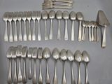 un grand nombre de cuillères et de fourchettes en argent disposées sur une table