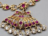a close up of a gold necklace with pink and white stones