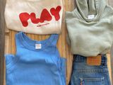 trois paires de jeans bleus et une chemise blanche avec le mot « play » imprimé dessus