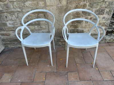 deux chaises blanches placées l'une à côté de l'autre sur un sol en briques