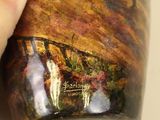 a person holding a coffee cup with a painting on it