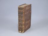 an old book sitting on top of a table next to a white wall