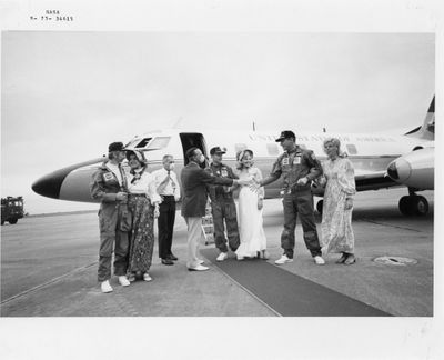 photographie en noir et blanc d'un groupe de personnes debout devant un avion